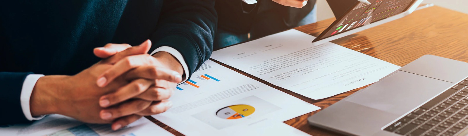 pie charts and documents on a desk next to a laptop computer