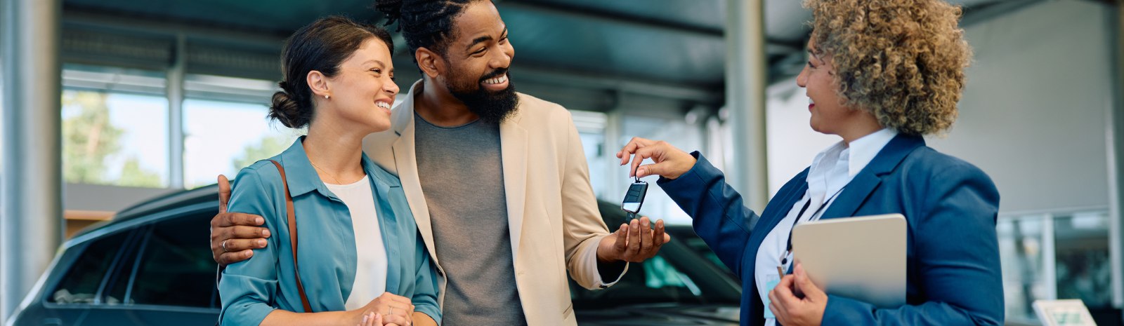 a couple being handed keys to a new vehicle