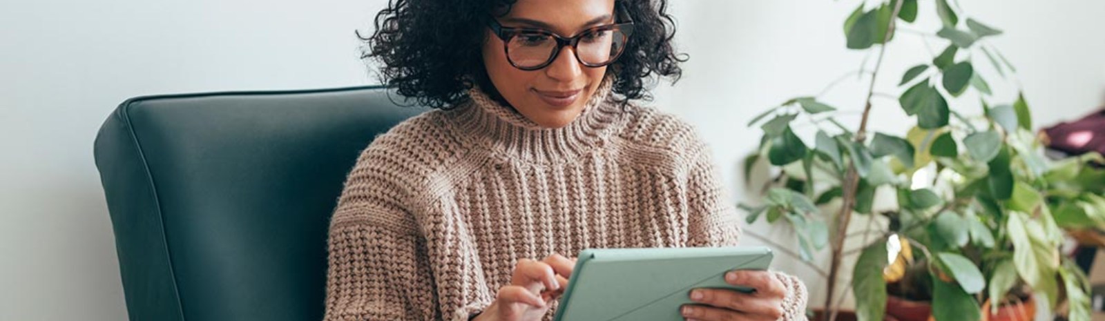 A woman wearing glasses working on her laptop.